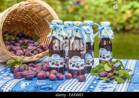 Bottiglie con il piccante salsa di prugne sul tavolo da giardino Foto Stock