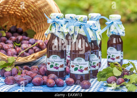 Bottiglie con il piccante salsa di prugne sul tavolo da giardino Foto Stock