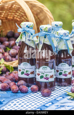 Bottiglie con il piccante salsa di prugne sul tavolo da giardino Foto Stock