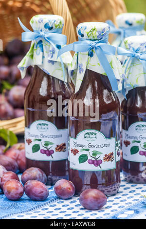 Bottiglie con il piccante salsa di prugne sul tavolo da giardino Foto Stock