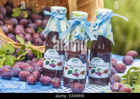 Bottiglie con il piccante salsa di prugne sul tavolo da giardino Foto Stock