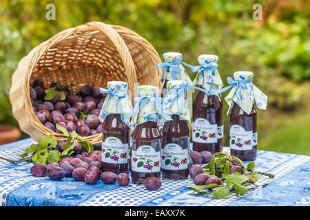 Bottiglie con il piccante salsa di prugne sul tavolo da giardino Foto Stock