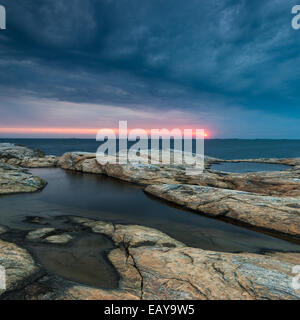 Costa rocciosa con drammatica cielo durante il tramonto Foto Stock