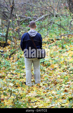 Un uomo si erge nel bosco su foglie verdi Foto Stock