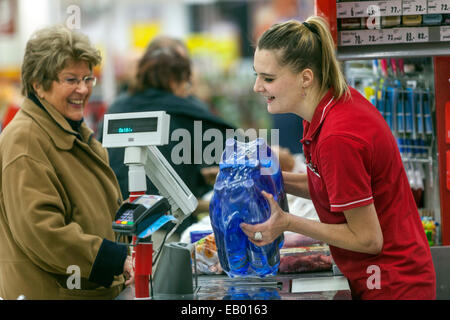 Persone donna anziana che fa acquisti al supermercato Cassiere donna legge codici a barre di bottiglie d'acqua Foto Stock