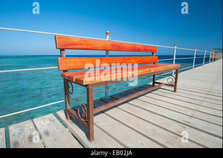 Panca in legno posto sul molo al tropical beach resort Foto Stock