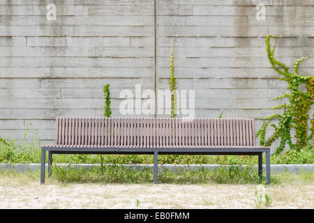 Lungo sedile di fronte un muro bianco con vite rampicante Foto Stock