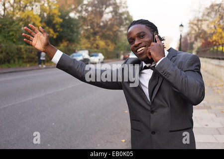 Business man salutando un taxi sul telefono. Foto Stock