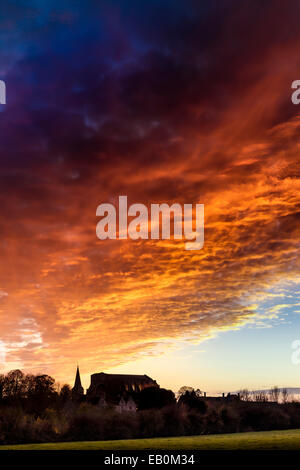 Malmesbury, Wiltshire, Regno Unito. Il 23 novembre 2014. Il cielo diventa arancione come il sole tramonta sull'abbazia nel Wiltshire cittadina collinare di Malmesbury. Credito: Terry Mathews/Alamy Live News Foto Stock