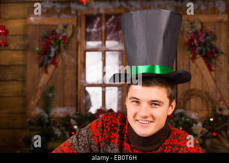 Close up bello sorridente Giovane con Black Hat, guardando la telecamera, davanti la parete in legno e vetro con natale Foto Stock