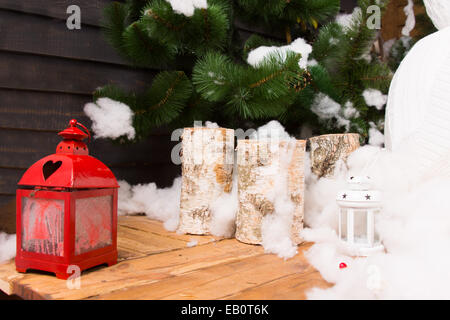 Decorazione le candele di Natale colorati e lanterna rossa su un tavolo in legno nella parte anteriore di un albero di Natale con la neve Foto Stock