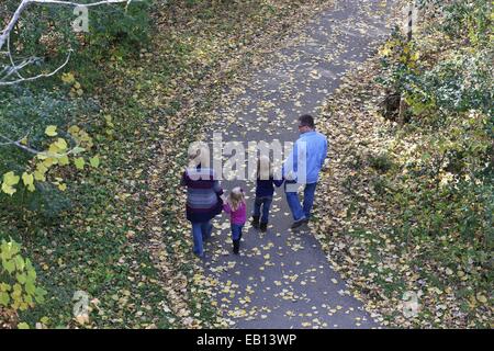 Una giovane famiglia a piedi su un percorso, come visto da sopra e da dietro. Foto Stock