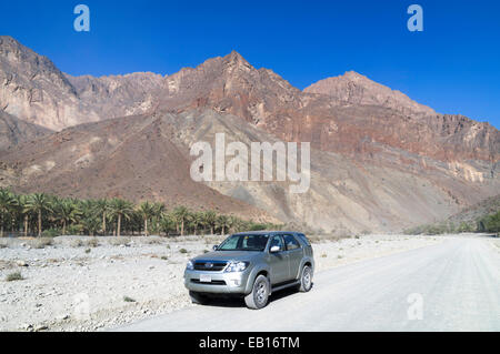 Auto sulla strada attraverso Wadi Sahtan come nelle montagne Hajar, Oman Foto Stock