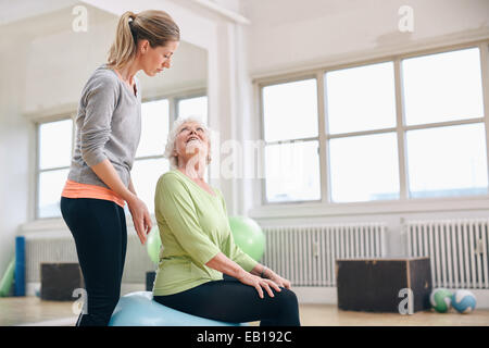 Ritratto di una femmina di istruttore di palestra aiuta una donna più anziana. Ritratto di una donna come tuo allenatore assistere senior donna esercita in materia di salute Foto Stock