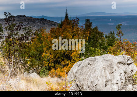 Vista autunnale del Krizevac (Cross) montagna a Medjugorje in Bosnia ed Erzegovina: marroncina alberi, erbe infestanti verdi, arancione e giallo di foglie e di rocce grigie Foto Stock