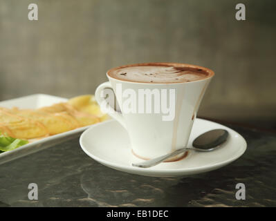 Tazza di cioccolata calda con arte latte cremoso in cafe Foto Stock