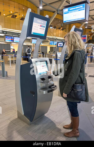 Donna che utilizza la compagnia aerea elettronica check-in self-service presso l'Aeroporto Internazionale di Vancouver (YVR). Foto Stock