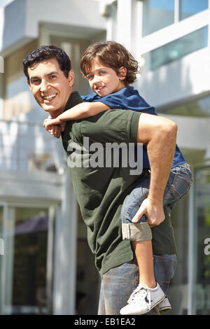 Padre Felice che porta il suo figlio sulla sua schiena per un piggyback ride Foto Stock