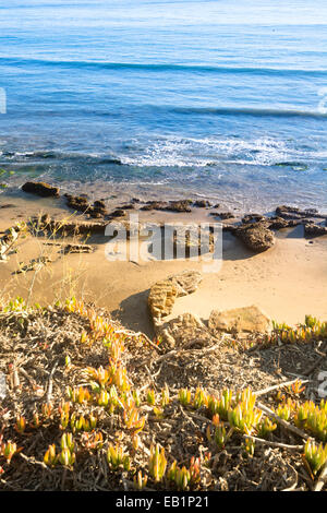 Come il sole tramonta al crepuscolo si getta a bassa, giallo luce lungo una bellissima spiaggia di Santa Barbara in California. Foto Stock