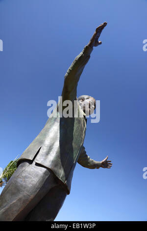 Un insolito vista di una statua di Nelson Mandela con braccia aperte e cielo blu dietro. Foto Stock