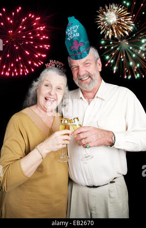 Coppia senior un po' bevuto il champagne a una festa di Capodanno. Sfondo nero. Foto Stock