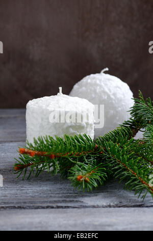 Due candele bianche sui pannelli con ramo di pino, natale Foto Stock