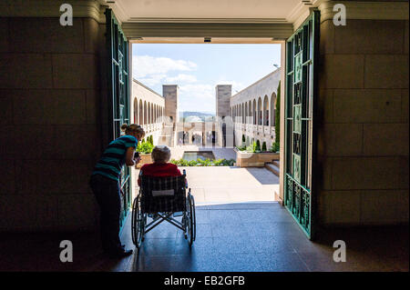 Una signora anziana che guardano sul cortile Memorial e il Memorial Pool dalla sala della memoria. Foto Stock