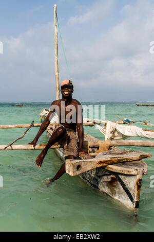 Un pescatore mori il suo legno vela trimarano dhow nei fondali bassi al tramonto. Foto Stock