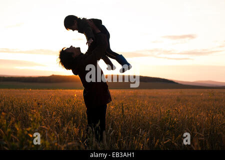 Mari padre e figlio giocando in campo rurale Foto Stock