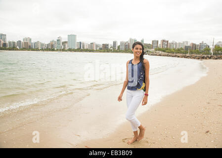 Donna sorridente camminando sulla spiaggia urbana Foto Stock