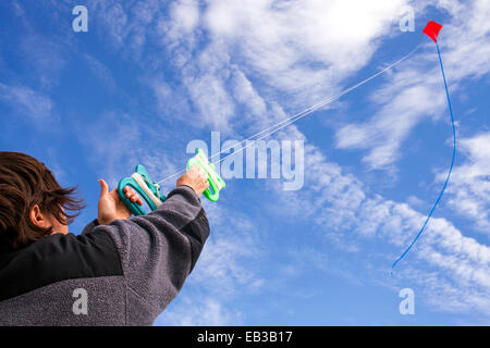 Basso angolo di visione dell uomo caucasico aquilone volante nel cielo blu Foto Stock