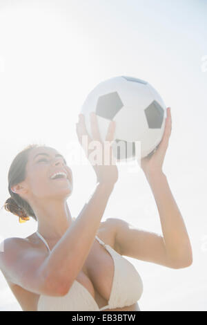 La donna caucasica tenendo palla calcio all'aperto Foto Stock