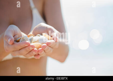 Ravvicinata di una donna caucasica holding conchiglie in spiaggia Foto Stock