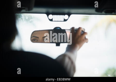 La donna caucasica regolazione dello specchietto retrovisore in auto Foto Stock