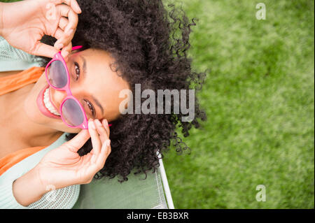 Elevato angolo di visione della donna azienda occhiali da sole in cattedra all'aperto Foto Stock