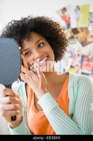 Donna sorridente ammirando se stessa in specchio Foto Stock