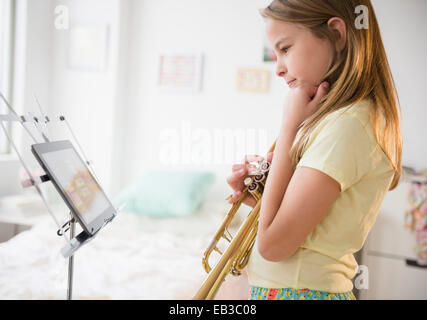 Ragazza caucasica praticando la tromba con tavoletta digitale Foto Stock