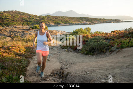 Donna che fa jogging lungo un sentiero costiero, Corsica, Francia Foto Stock
