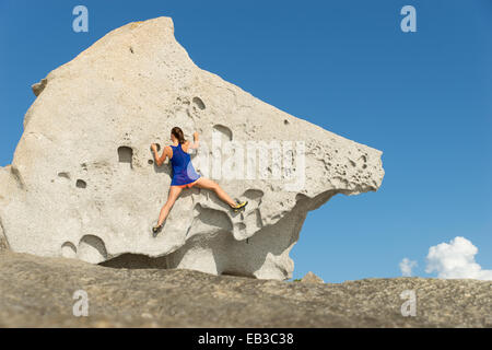 Vista posteriore di una donna che sale una grande roccia, Corsica, Francia Foto Stock