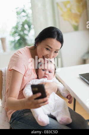 Asian la madre e il bambino tenendo selfie in home office Foto Stock