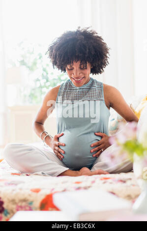 Africana incinta madre americana mentre tiene il suo stomaco Foto Stock