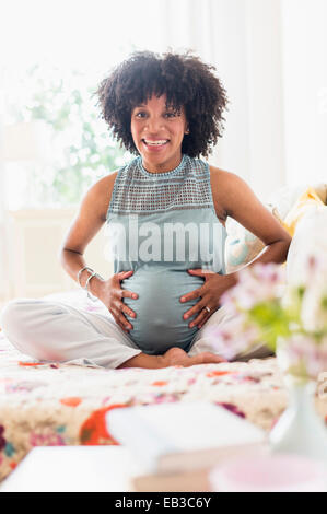 Africana incinta madre americana mentre tiene il suo stomaco Foto Stock