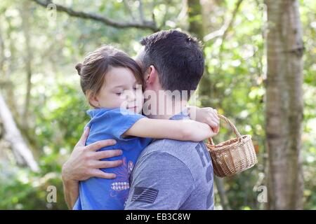 Ragazza in piedi nella foresta abbracciando il suo padre Foto Stock