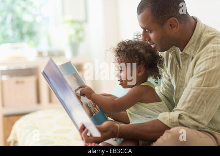 Padre e figlia la lettura di un libro sul letto Foto Stock