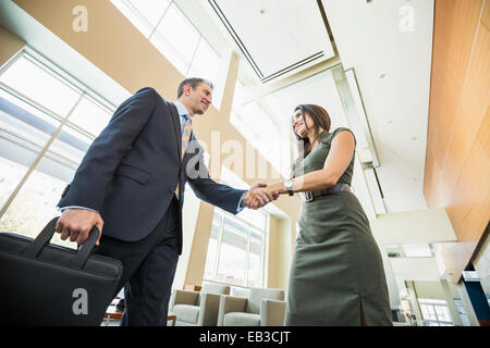 Basso angolo vista di uomini di affari che stringono le mani nella lobby di office Foto Stock