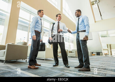 Basso angolo di visione degli imprenditori parlando nella lobby di office Foto Stock