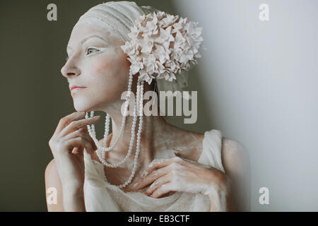 Ritratto di giovane donna che indossa il make up, greasepaint, perline e decorazioni di orecchio che assomigliano a infiorescenza Foto Stock