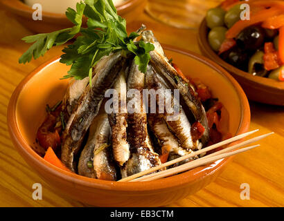 Pila di sardine fritte con il ramo di prezzemolo e bastoncini nel recipiente Foto Stock