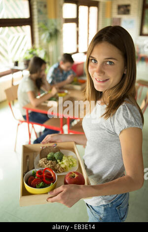 Studente portante vassoio pranzo in mensa scolastica Foto Stock