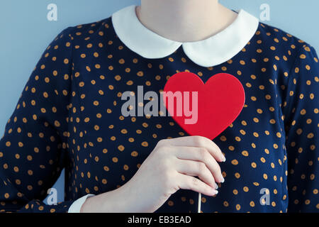 Donna che indossa la polka dot dress holding cuore forma oggetto Foto Stock